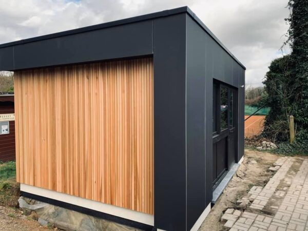 Bureau de jardin à toit plat avec façades noires et bardage en bois clair
