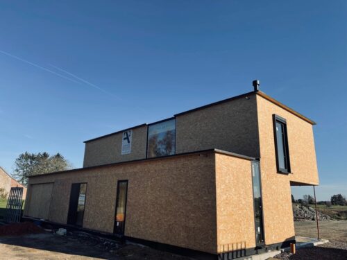 Maison aux formes géométriques en briques claires avec toit plat et châssis noirs