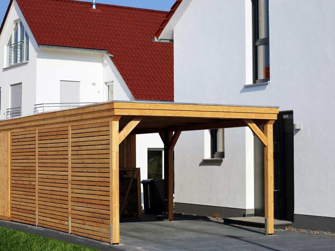 Carport fermé en bois devant une maison moderne en crépi blanc