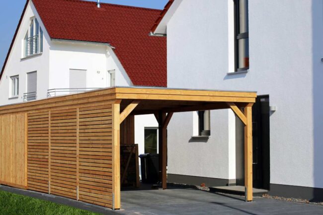 Carport fermé en bois devant une maison moderne en crépi blanc