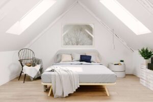Grenier mansardé aménagé en chambre avec les murs blancs et un lit au centre