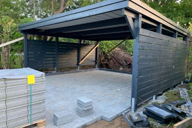 Carport en bois teinté noir avec un abri intégré en construction