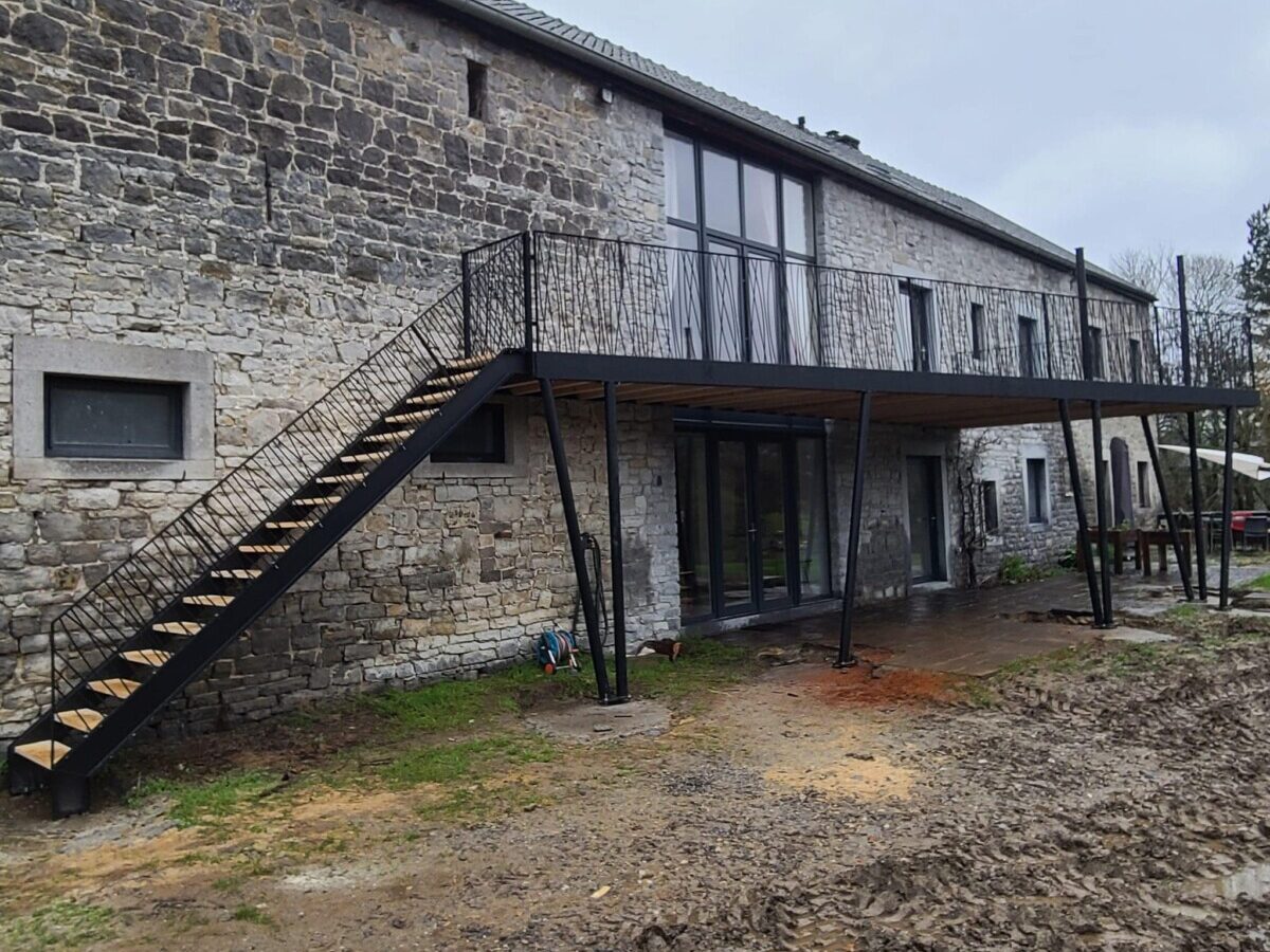 Terrasse en bois avec garde corps en aluminium noir au premier étage d'une maison en pierre