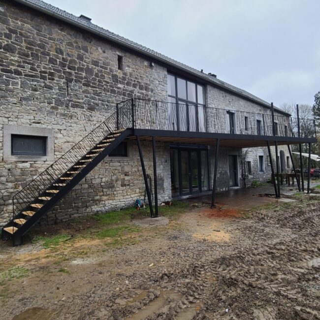 Terrasse en bois avec garde corps en aluminium noir au premier étage d'une maison en pierre