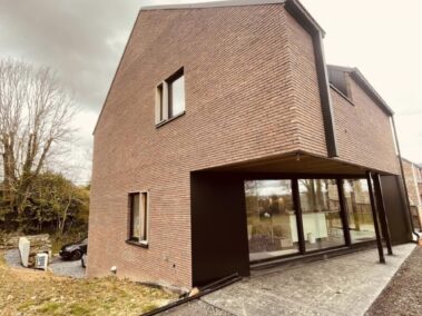 Maison en brique rouge avec emplacement de terrasse pas encore construite.