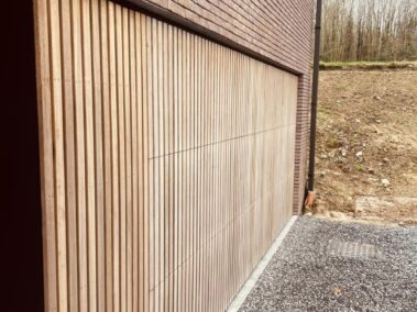 Mur d'une maison en brique rouge avec un bardage en bois clair