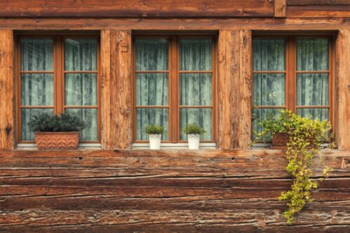 Vue sur les trois fenêtres avec châssis en bois et pots de fleur d'un chalet